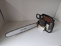 Side overview of chainsaw showing guide bar, chain and housing
