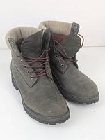 Front angled view showing the grey leather boots with red laces and padded collar.