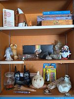 Wide shot of shelves showing various decorative items including the Berlin Wall box, figurines, walkie talkies, and kitchen salt shaker.