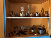 Shelf containing various vintage compasses, brass ashtrays, and decorative items.