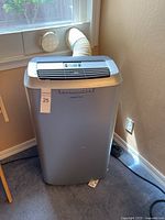 Front view of silver Edgestar portable air conditioner with vent hose connected to window.