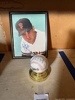 Framed photo of Will Clark with autographed signature and signed baseball on display stand.
