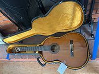 Full view of Yamaha acoustic classical guitar in hard shell case with yellow interior lining.