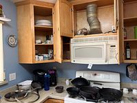 Countertop with several cast iron pans including skillets and wok pan, a kettle or pot, and various small kitchen items