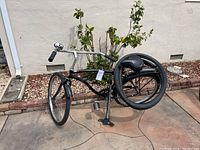 Side angle of black Micargi beach cruiser bike on pavement showing frame, front wheel, pedals, and fenders.