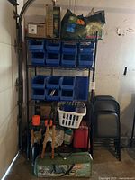Full view of metal storage rack with items on shelves and foldable chairs stacked beside it