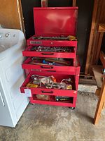Red Remline tool chest with drawers open showing various hand tools organized inside.