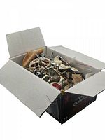 Wide angle photo showing the open box full of assorted broken costume jewelry pieces including necklaces, bracelets, and loose parts.