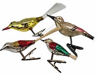 Four vintage glass bird Christmas ornaments viewed from above, showing color and condition of each.