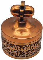 Round copper lidded trinket dish with engraved patterns on the sides and double-loop handle on lid, showing front and top side view