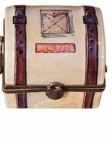 Front view showing cream-colored porcelain with painted brown straps, stitched postal labels, and a red-orange 'New York' label.