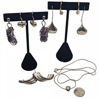 All items displayed with black earring stands showing earrings and necklace with coin for scale.