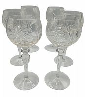 Front angled view of six crystal wine glasses showing detailed etched design on bowl and faceted stems.