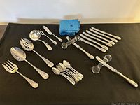 Overview of flatware pieces, crystal holders and cloth bag holders on black background