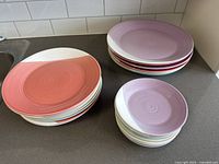 Stack of pastel-colored Royal Doulton plates showing the variety of sizes and colors including pink, purple, and white with spiral design.
