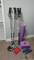 Full fitness item set showing two pairs of walking poles, yoga mat, hand weights, ankle weights, resistance band, and yoga blocks
