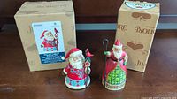Two Jim Shore Santa Claus figurines displayed front and center with their original boxes behind.