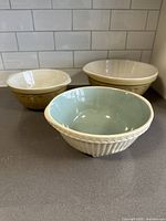 Three ceramic mixing bowls shown on countertop, cream colored with decorative embossing and one Easimix bowl with pale green interior.