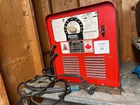 front view of red Lincoln Electric AC-225-S arc welder with cables and clamps