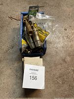 Collection of brass pipe fittings and couplers in plastic container, with box labeled 156.