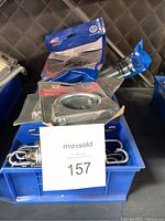 Blue bin containing metal spring tubes, muffler clamps, Mounting bracket, and assorted springs.