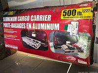 Box of Erickson aluminum cargo carrier showing product name, max capacity 500lb, and images of the carrier attached to vehicles.