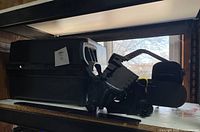 Photo of the Poulan Wild Thing 2375 gas chainsaw motor unit and black rectangular carrying case on a shelf.