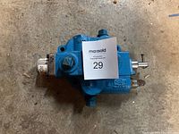 Top view of the blue hydraulic pressure control valve with visible connection ports and adjustment bolts.