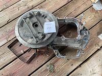 Photo showing metal snowmobile crankcase with visible wear and some corrosion, laid on wooden surface.