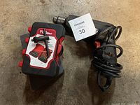 Black & Decker electric drill coiled with power cord and set of drill bits in plastic case