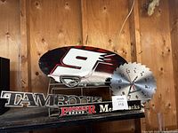 Metal NASCAR #9 tacker sign, Tamrock metal sign, Pioneer Brand Meat Snacks metal shelf, and saw clock with eagle logo