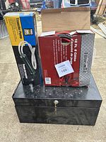 Power Fist transfer pump and Mr. Blacksmith booster cables boxed items sitting on the black metal toolbox.