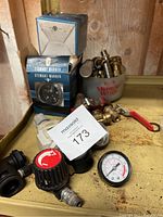 Photo showing oil pressure gauges, an hour meter box, and various valves and fittings organized on a wooden surface.
