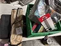 Photo showing black tool case, canvas roll, and green crate with various items including foam backer rod bag and pressure gauges.