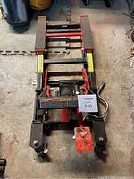 Front view of the MotoMaster motorcycle/ATV jack showing the lifting platforms, wheels, and pedal lever with label.