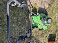 Top-down view of the lawn mower showing the handlebar and control cables over grass.