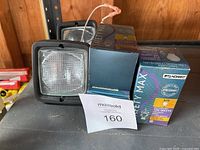 Photo of one square Caterpillar halogen lamp with clear textured glass and three Standard Safety Max incandescent bulb boxes