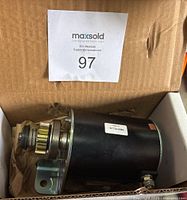 Electric starter motor AG21C4 with gear and mounting bracket in cardboard box, showing side profile and label.