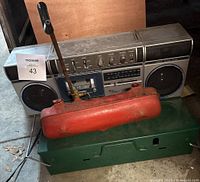 Coleman camp stove, red fuel tank, and portable stereo shown together with garage background