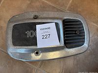 Top view of silver metal air cleaner housing cover with '1000' marking and black vent section.