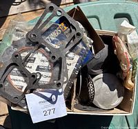 Box open showing carburetor gaskets, piston rings, and packaging material inside