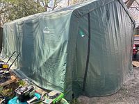 Overall exterior view of green ShelterLogic shelter with equipment nearby