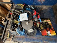 Lot overall showing multiple metal C-clamps, blue pulley wheels, and plastic clamps