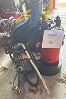 Water pump with hoses attached shown from an angle, highlighting the red and black sections of the pump with yellow cord.