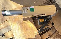 Top view of DeWalt 7710 radial arm saw showing arm and motor assembly on wooden surface under sunlight.