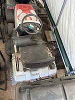 Top view of the Honda riding mower showing black seat, steering wheel, and black blower attachment on right side.