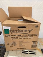 Closed cardboard box of Optimum roof exhaust trap, brown color, model OPTI-C4 with product branding and description.
