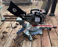 Full view of King Canada sliding compound miter saw showing saw blade, laser guide, retractable extension, and dust collection bag on wooden deck.