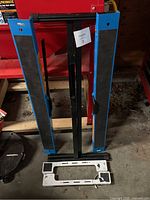 Blue and black folding sawhorses set against a red background with two white rectangular board pieces in front