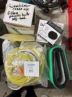 Top-down view of multiple items including green air filter, Yellow fuel lines, labeled box for weed eater carbs with filter, primer bulb and adjustment tool.